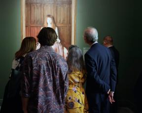 Visitors in "Fashioned by Sargent" exhibition, gathered closely around portrait of a young girl in a dress
