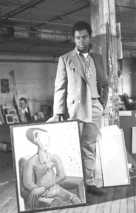 A man stands in front of a painting that has been defaced with white paint.