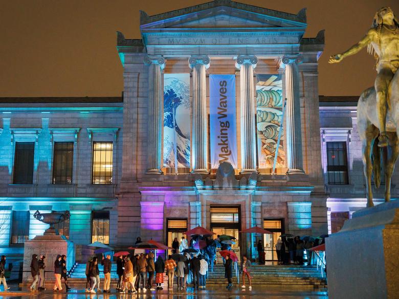 Visitors lined up outside Huntington Avenue Entrance, many holding umbrellas, waiting to get inside to MFA Late Nites