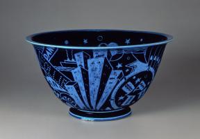 A glazed, black porcelain bowl decorated with brilliant blue incised motifs of New York City attractions