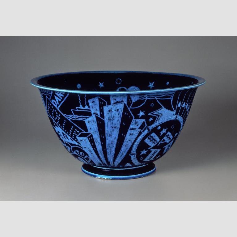 A glazed, black porcelain bowl decorated with brilliant blue incised motifs of New York City attractions