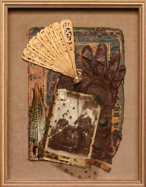 A framed mixed media artwork of a Victorian photograph covered in lace, a leather glove, and an aged fan.