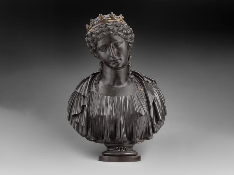 A dark metal bust of Cleopatra wearing a crown with a snake on the base