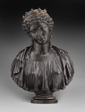A dark metal bust of Cleopatra wearing a crown with a snake on the base.