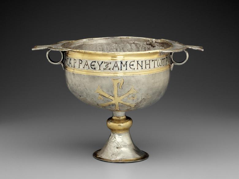 Metal and gold cup with handles on its sides.