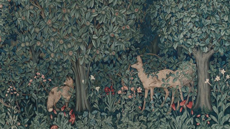 A dark forest scene with two deer standing beneath the verdant leaves of lush trees.