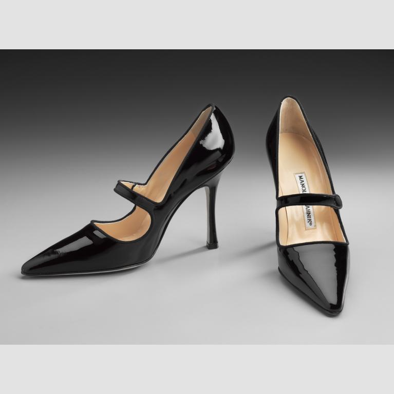 A pair of black patent Mary Jane heels with a pointed toe. 