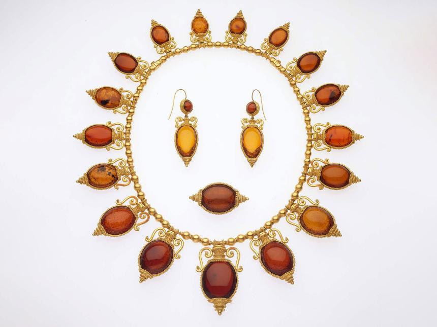 arrangement of necklace, earrings, and a ring that are made with an amber colored stone