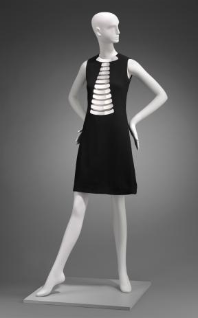 A photo of a mannequin wearing a black dress with a metallic silver chest detail.