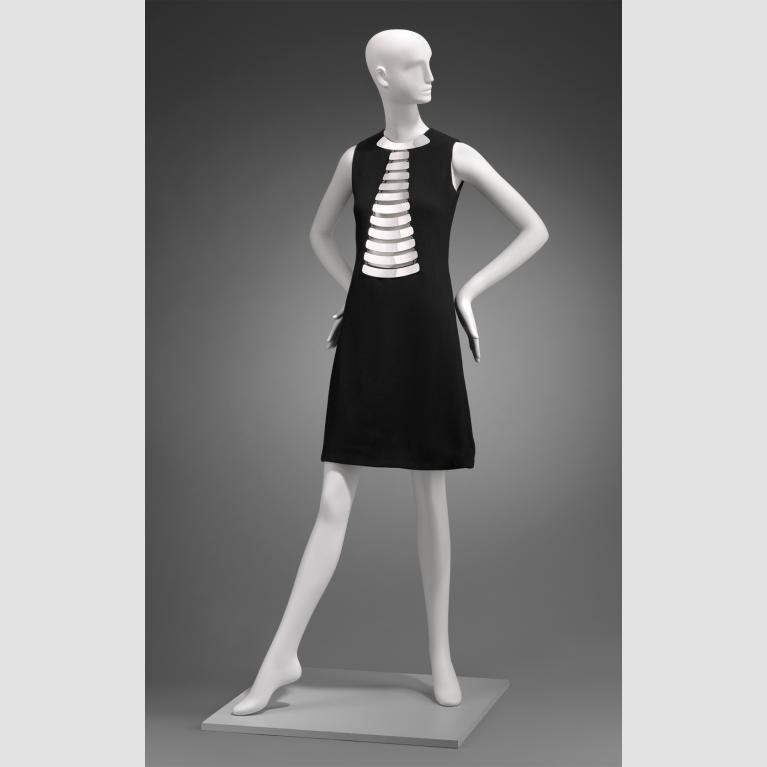 A photo of a mannequin wearing a black dress with a metallic silver chest detail.