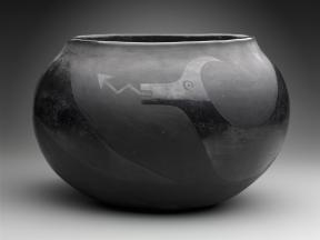 A blackware bowl is decorated with a polished with an Avanyu or water serpent