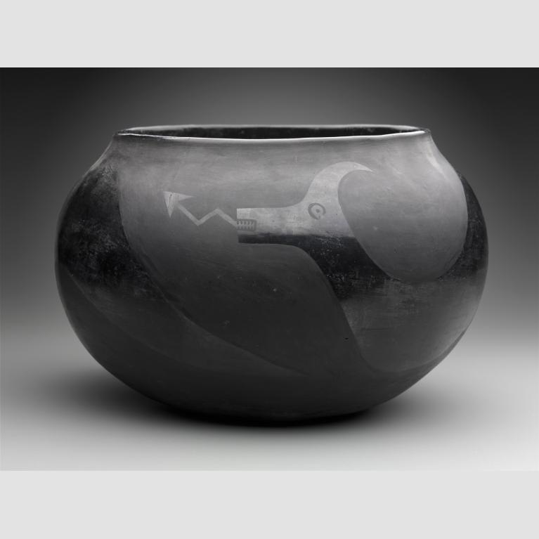 A blackware bowl is decorated with a polished with an Avanyu or water serpent