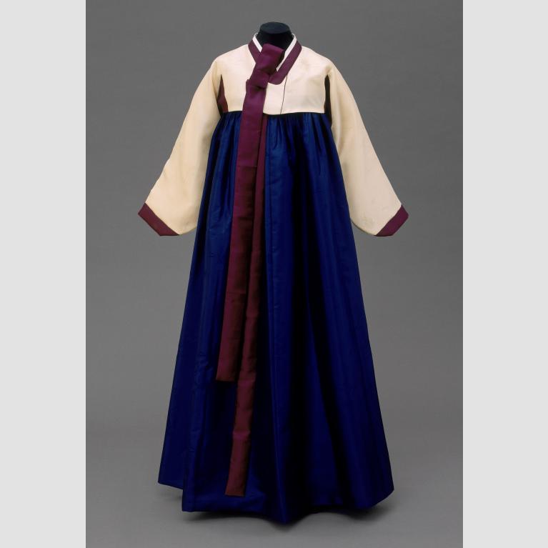 A traditional Hanbok gown with a white top and sleeves, a blue skirt, and red fabric details.