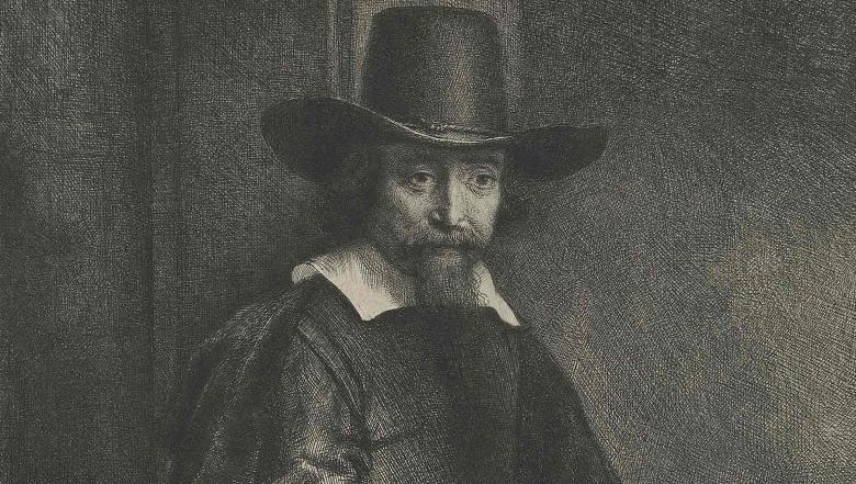 A bearded man wears a black hat and looks sternly at the viewer.