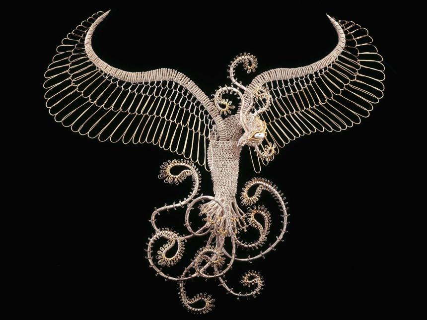 big silver neckpiece sculpted like a flying bird