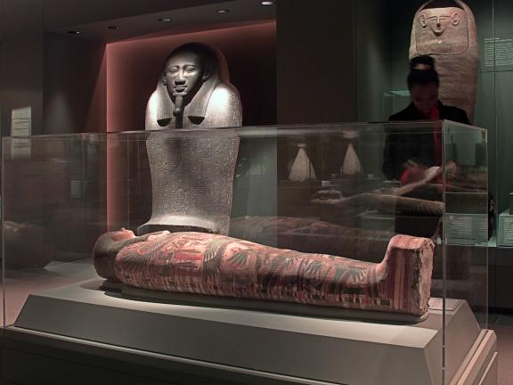 Installation view of the mummies gallery, people looking at mummies