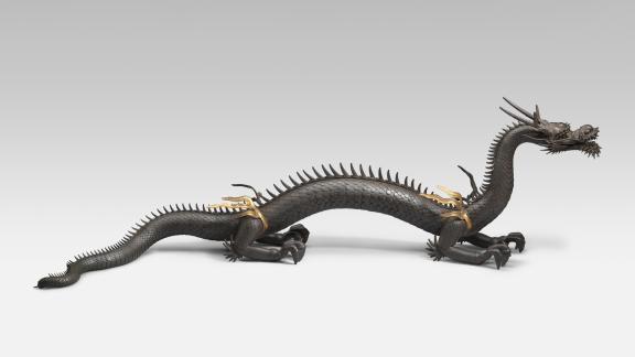 An iron, articulated model of a dragon with gilding. 