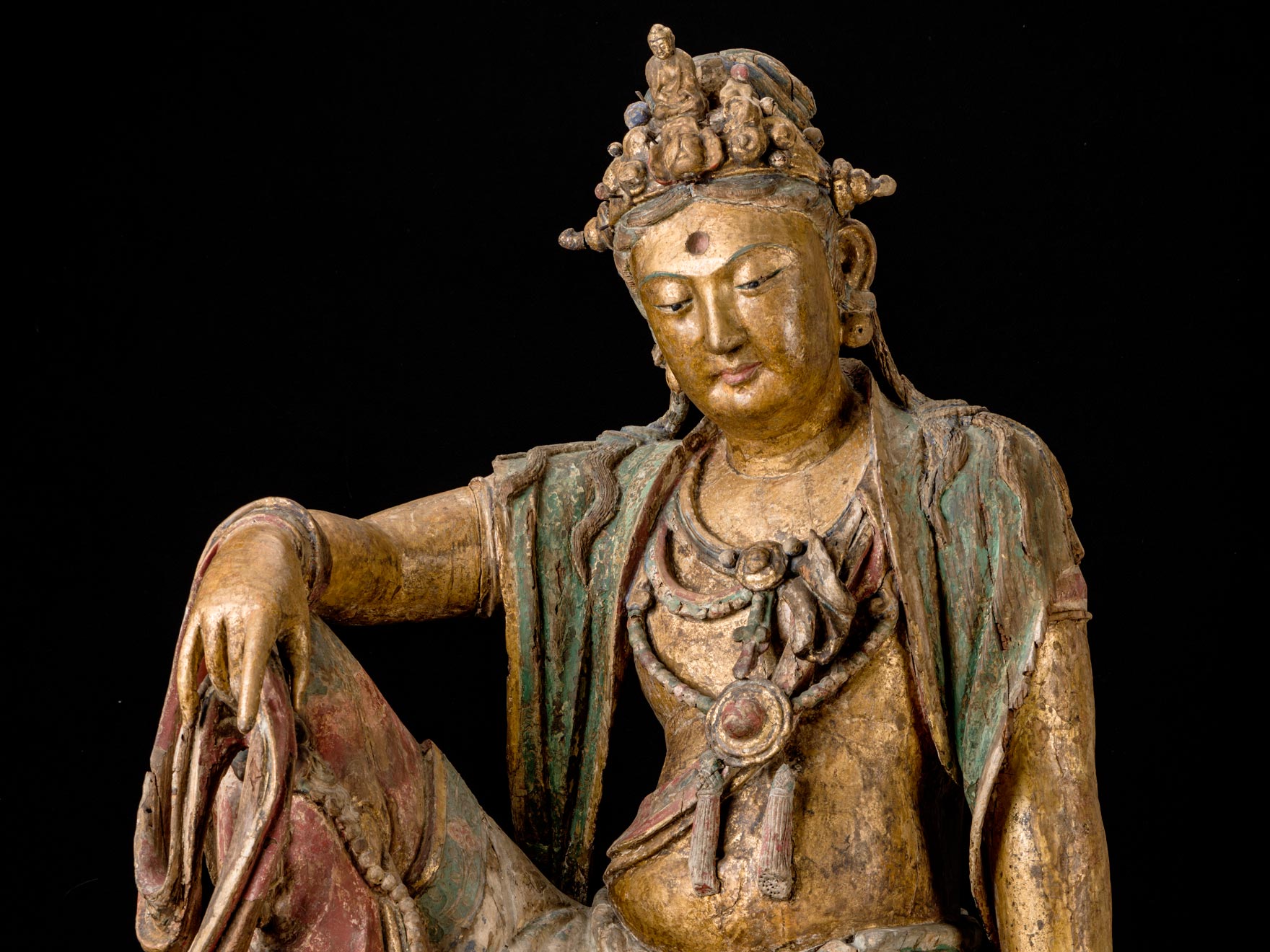 wooden sculpture depicting Guanyin in seated position with hand on one raised knee