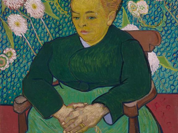 Vincent van Gogh painting featuring woman in green dress and hair in a bun, sitting on chair in front of green wall covered in white flowers