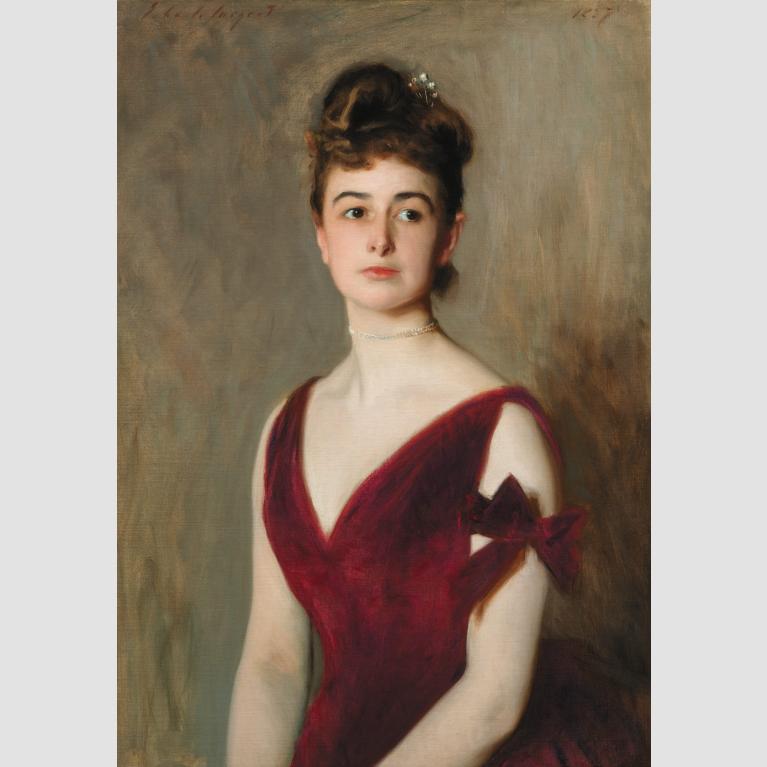 A woman sits for a portrait in a burgundy silk dress. 