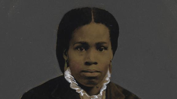An African American woman in a dark overcoat poses for a photo.