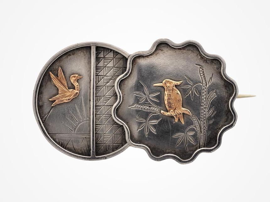silver brooch with two gold birds on it