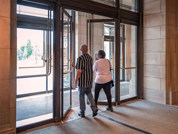 Two visitors exiting the museum through doors at the entrance