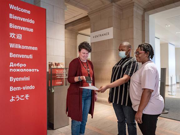 Museum staff person scanning tickets for two visitors