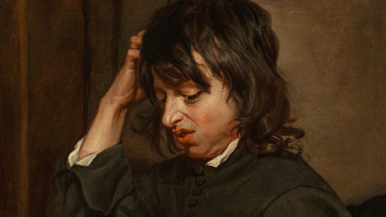 A young boy looks down disgustedly at his right hand, which is covered with dirt.