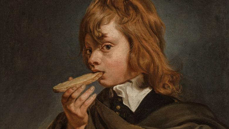 A young boy eats a piece of bread.