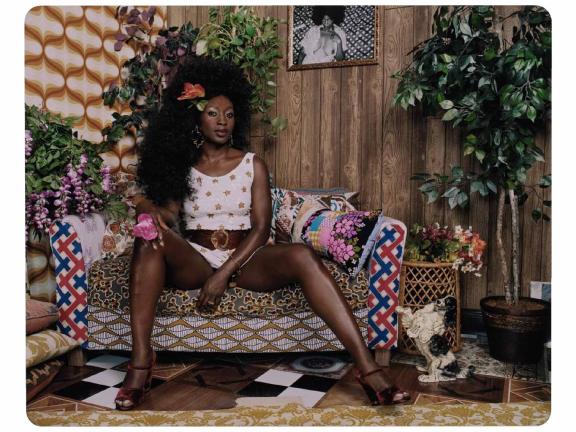 Painting of woman with big hair wearing white top and sitting on multi-patterned couch