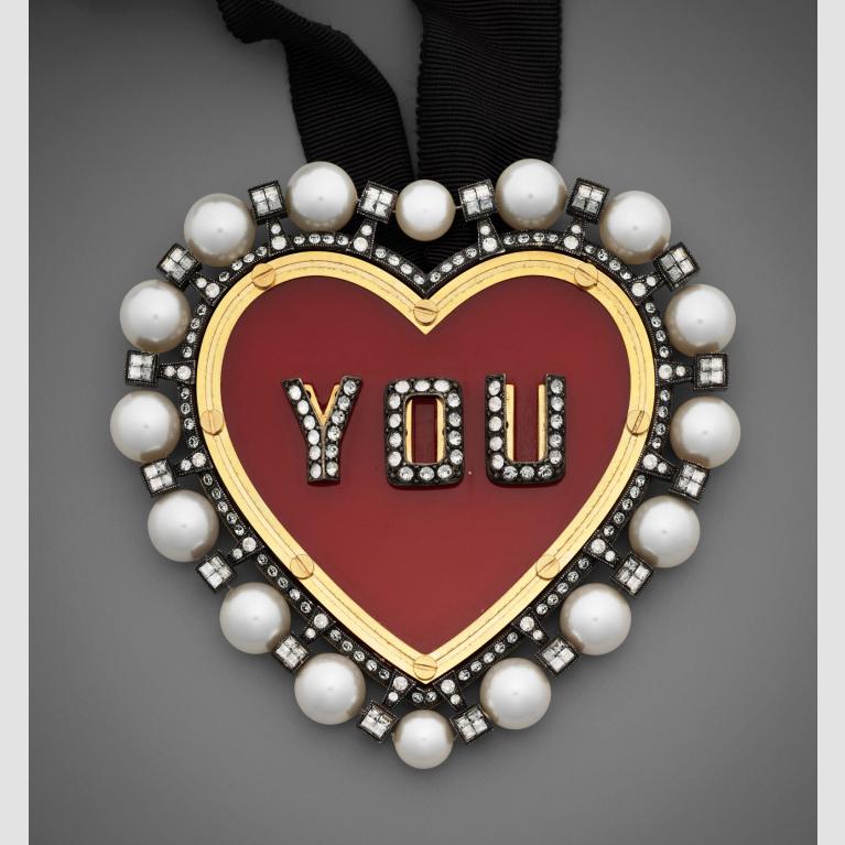 A heart-shaped necklace with the word "You" in the center. 