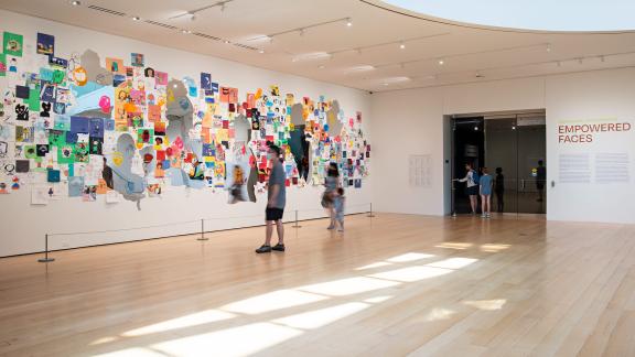 Museum visitors admiring the artwork of the Community Arts Initiative: Empowered Faces exhibition