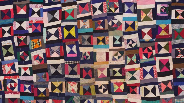 A quilt composed of multicolored triangles and squares.
