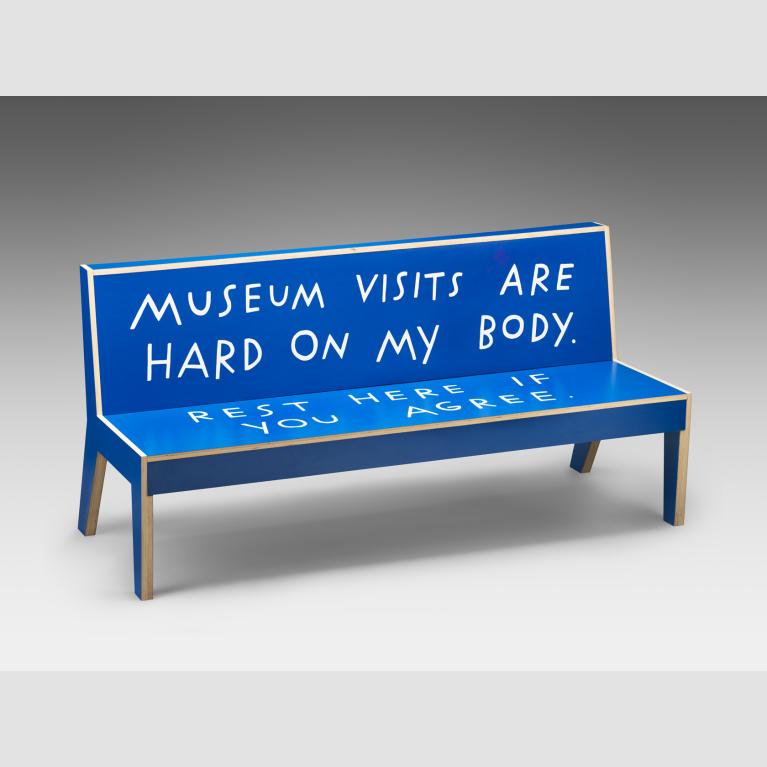 A blue bench written on with "Museum visits are hard on my body. Rest here if you agree."