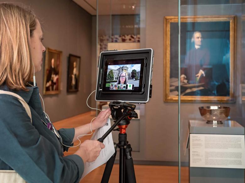 An MFA instructor operating a camera on a tripod pointed at Liberty Bowl in gallery case