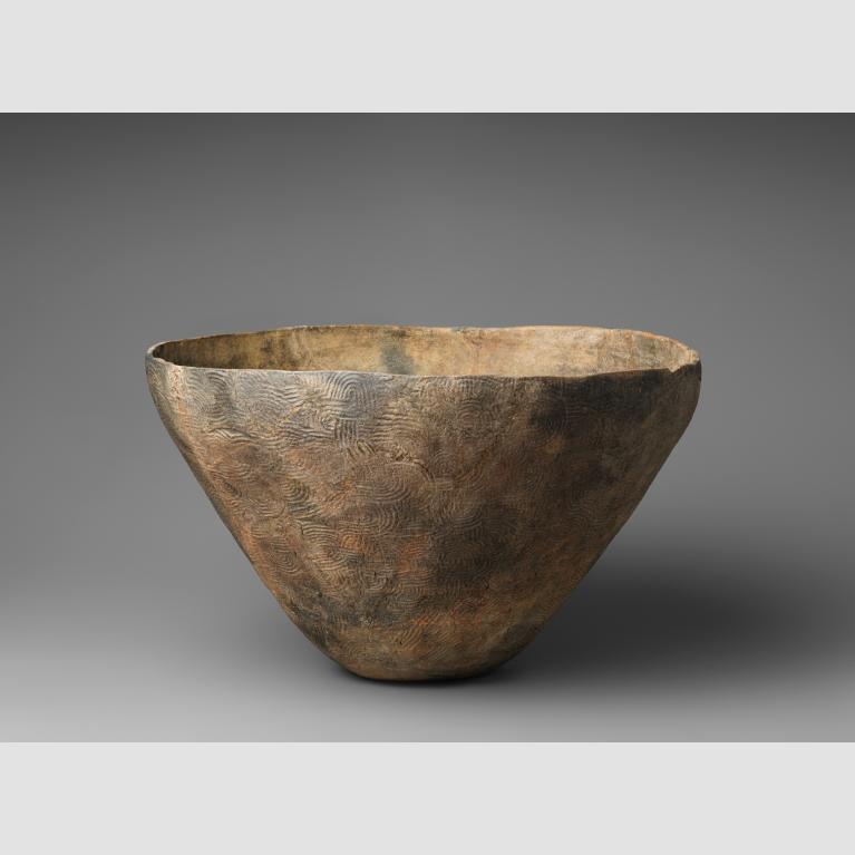 An earthenware bowl with a wide opening and engraved with swirls.
