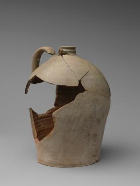 A cracked, reconstructed stoneware jug with handle and a large hole in its side.