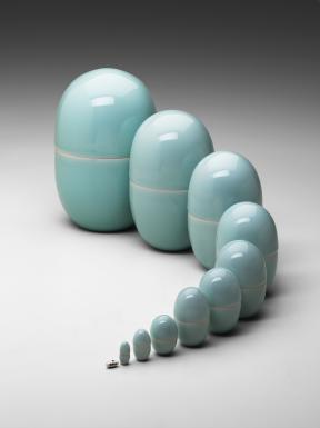 Eleven light-blue porcelain oval-shaped nesting boxes lined up in a curve and increasing in size from one to the next.