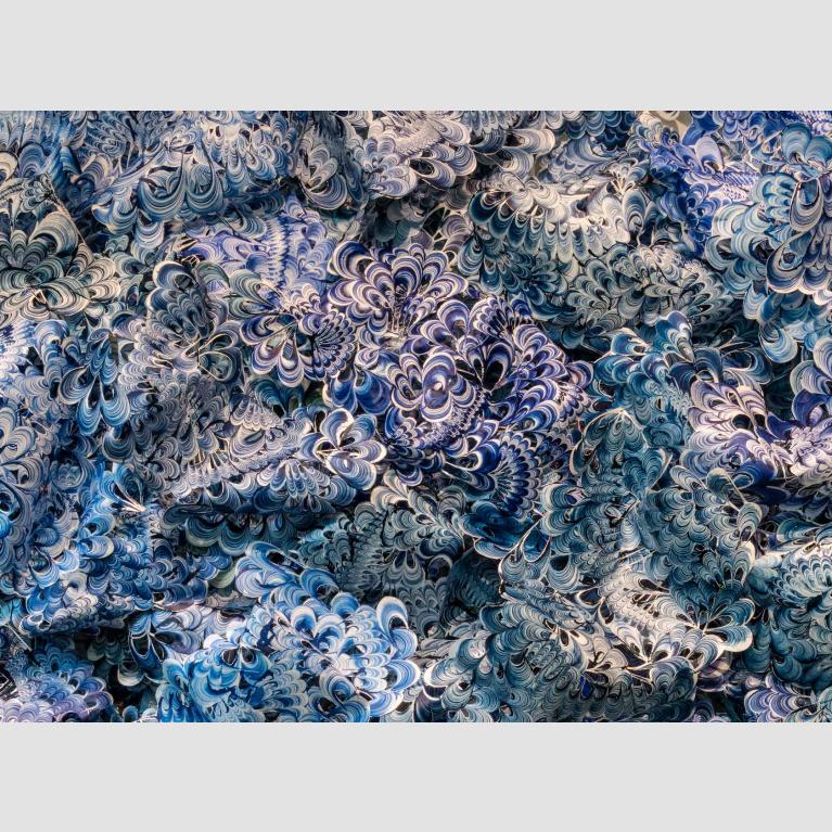 Blue-and-white shell-like pieces of plastic interlocked to resemble a wave. 