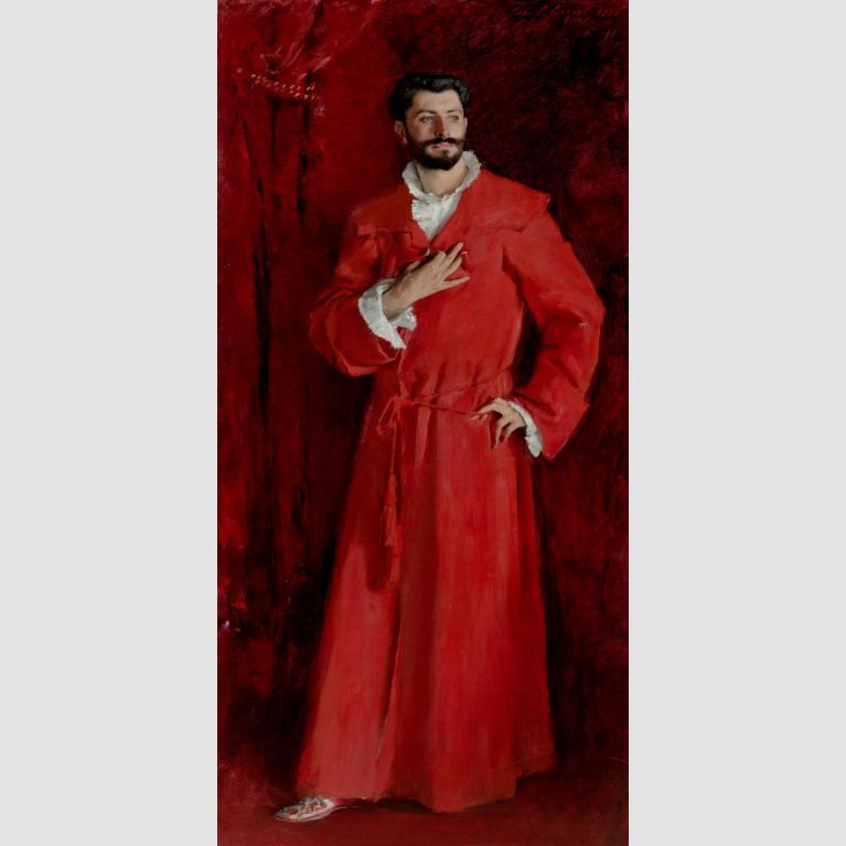 A man in a bright red robe stands against dark red velvet with his left arm akimbo and tight hand at his chest.