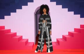 A model wears an Adidas outfit and stands against a bright, abstract tracksuit. 