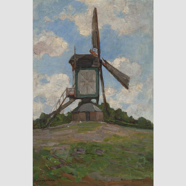 A three-sailed windmill spins at the top of a small hill. 