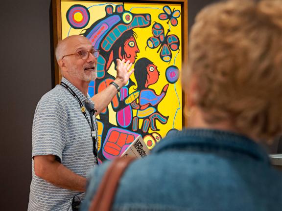 An MFA tour guide speaks to a tour group about Norval Morrisseau's Bear Father, Bear Son