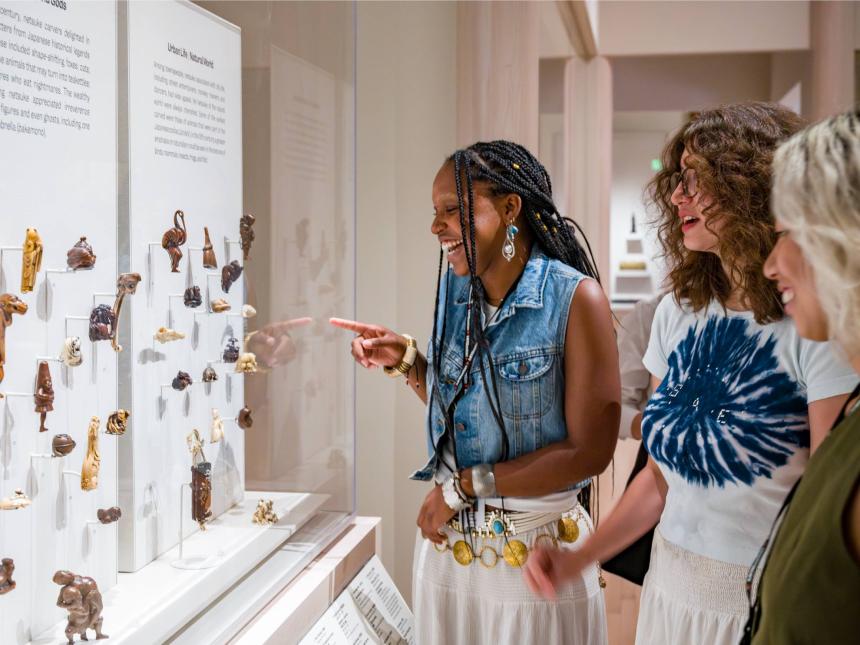 Visitors looking at various netsuke arranged in gallery case