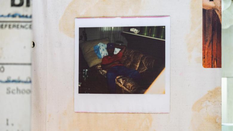 A darkened polaroid of a man lying on a sofa.