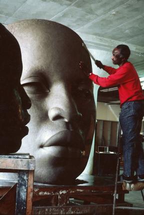 John Wilson working on clay sculpture head with African-American features and closely cropped hair 