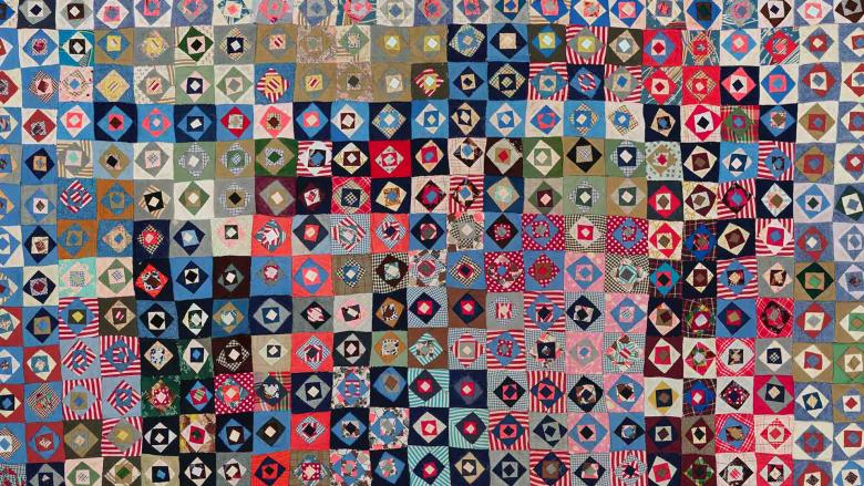 A quilt composed of multicolored squares, each with two contrasting circle inside of it.