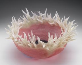 A pink glass bowl with translucent thorn-like tendrils surrounding its ridge.