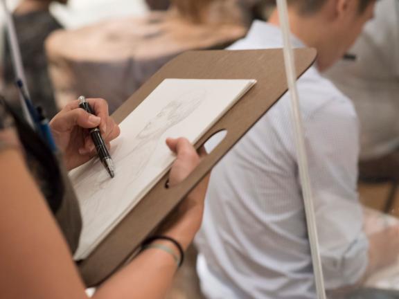 Student drawing figure on drawing board